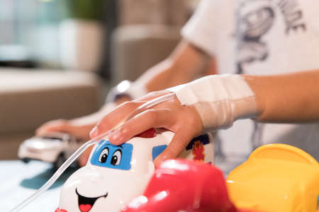 Child playing with toys in hospital with intravenous drip in his hands. Middle