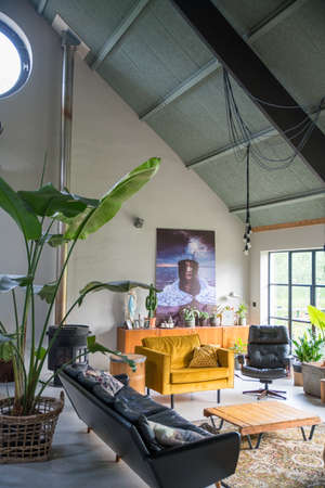 Trendy interior with midcentury modern vintage furniture. Big houseplants.