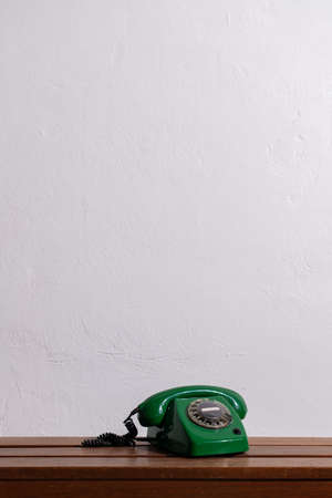 green retro telephone on a wooden table against a white wall. Copy space.の写真素材