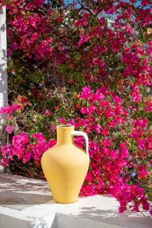 Bougainvillea flowers against a Portuguese house. Yellow vase.の写真素材