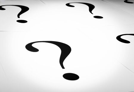 Printed question marks on the white paper spared on the table