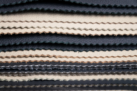 Layers of black and white leather samples with zigzag border cut, leather texture background