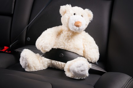 Teddy bear fastened in the back seat of a car, safety on the roadの写真素材