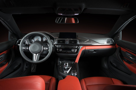 Modern luxury car Interior - steering wheel, shift lever and dashboard. Car interior luxury.Steering wheel, dashboard, speedometer, display. Red and black perforated leather cockpitの写真素材