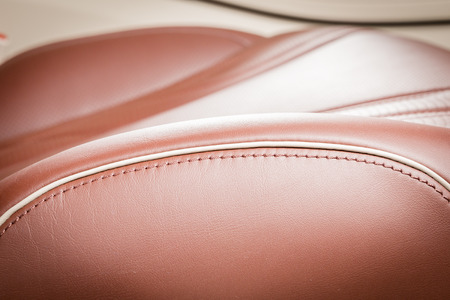Red perforated leather driver seat with stitching inside luxury car interior