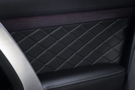 Modern luxury car  black leather interior. Part of  perforated leather car seat details. Car door wood panelsの写真素材
