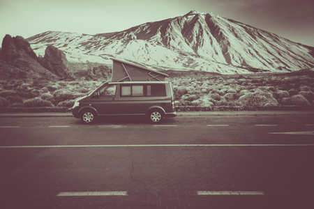 Small travel vehicle camping van or big car with folding rooftop with bed is parked under huge mountain formation. Tourism vacation and travel. Camper van and mountains landscapeの写真素材
