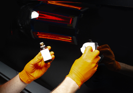 Car polish wax worker hands polishing car. Buffing and polishing vehicle with ceramic. Car detailing. Man holds a polisher in the hand and polishes the car with nano ceramic. Tools for polishingの写真素材