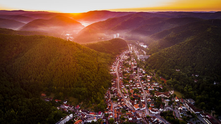 Aerial drone bird's eye view photo of european village of central europe with red roofs and cozy streets, beautiful natural morning sun lights and a fog in the valleyの写真素材