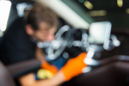 Blurred abstract background of a worker cleaning car interior dashboard with a brushの写真素材
