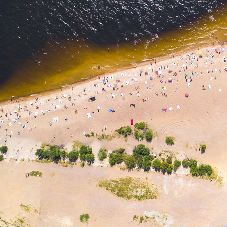 People bathing in the sun, swiming and playing games on the beach. Tourists on the sand beach. Aerial view of seashore and a beachの写真素材