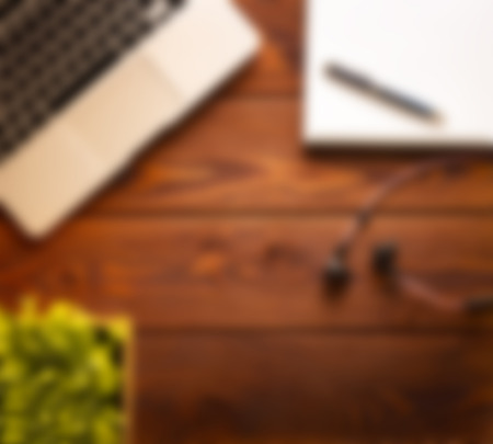 Abstract blurred background image of office workplace with laptop and notebook with wireless headphones on the wooden tableの写真素材