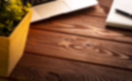 Abstract blurred background image of office workplace with laptop and notebook with a pen on the wooden surfaceの写真素材