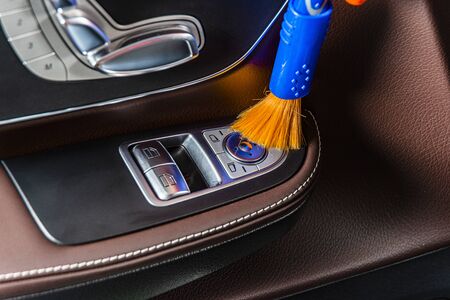 A man cleaning car interior panels and dashboard with a brush. Car detailing or valeting concept. Selective focus. Car detailing. Cleaning with sponge. Worker cleaning. Car wash concept solution to cleanの写真素材