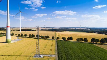 Aerial view of windmill against blue sky with clouds. Wind turbine farm and a road between...