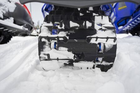 Close-up of a snowy caterpillar of a snowmobile on the ski resortの写真素材