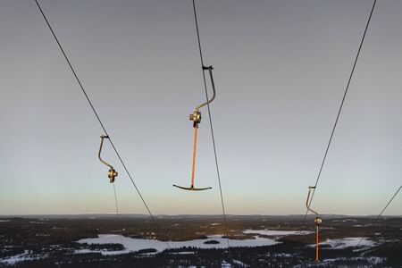 Hooks are hanging on a lift cable in a ski resort in winter with a beautiful sunset skyの写真素材
