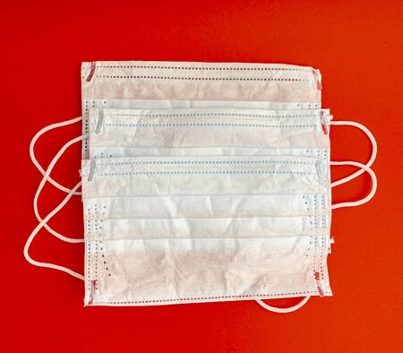Set of three White medical masks. Medical protective masks over red background. Healthcare and medical concept. Protective face mask or medical mask. Protective shielding bandageの写真素材