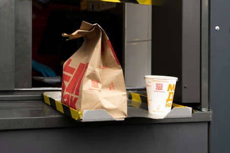 Sankt-Peterburg, Russia, 18/07/2020: McDonalds service the Drive-Thru due to coronavirus. Employee in gloves, order in window. Contactless transfer.のeditorial素材