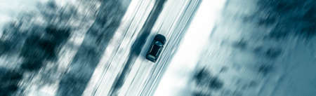Aerial view of a car on winter road. Winter landscape countryside. Aerial photography of snow forest with a car on the road. Captured from above with a drone. Aerial photo. Quadcopter. Aerial car view. Motion blur effectの写真素材