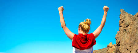 Happy celebrating winning success woman standing elated with arms raised up above her head in...