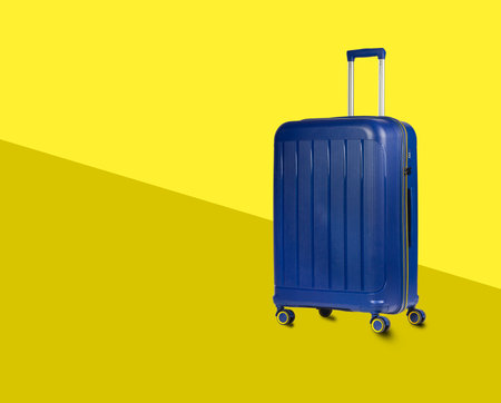 Blue Plastic Trolley Travel Case with Metal Handle over yellow stylish backgroundの写真素材