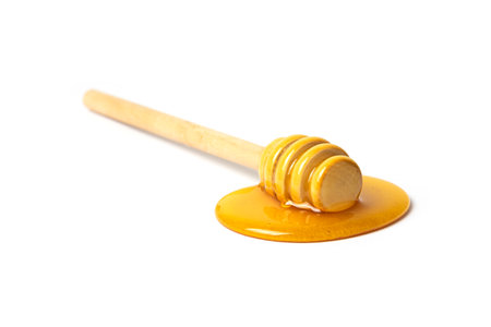 Honey dripping from dipper wooden honey stick isolated white backgroundの写真素材