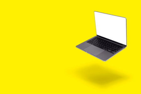 Photo of realistic modern laptop with blank white screen floating in front of a yellow backgroundの写真素材
