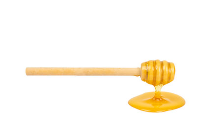 Honey dripping from dipper wooden honey stick isolated white backgroundの写真素材