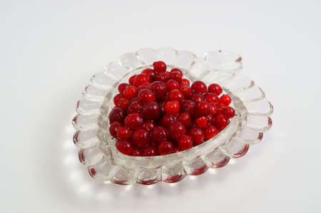 Berry a cowberry in a vase in the form of heart on a white background         の写真素材