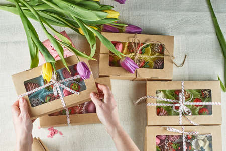 Edible handmade gifts, strawberries in chocolate, macaron, decorated with tulips in a gift box      ...