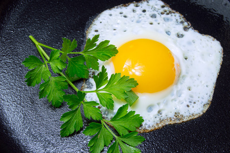 Fried egg with parsley on pan for breakfast close upの写真素材
