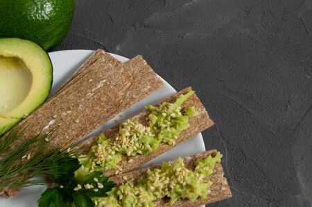 Crispbreads with smashed avocado sprinkled sesame seed close up top viewの写真素材