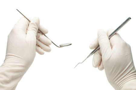 hands of dentist holding his tools during patient examination isolatedの写真素材
