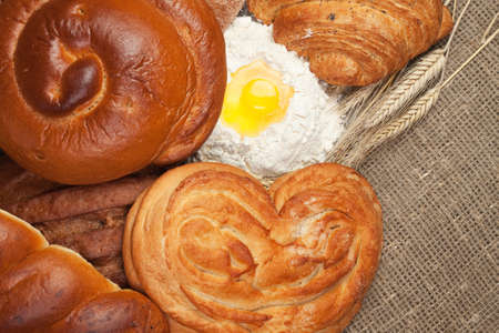 variety of fresh bread with ears of rye and flour background