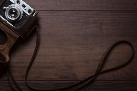 wooden background with retro still camera in case