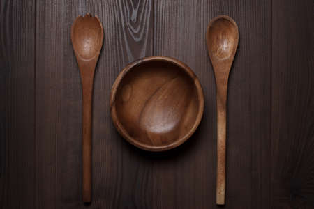 wooden salad bowl and two spoons on the brown tableの写真素材