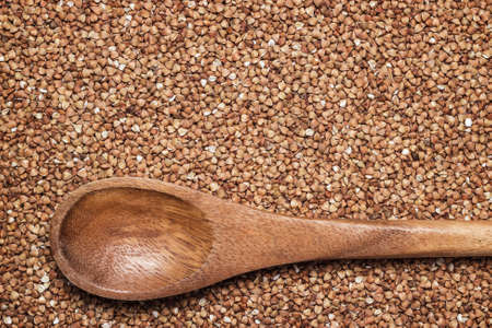 buckwheat background with brown wooden spoon food preparationの写真素材