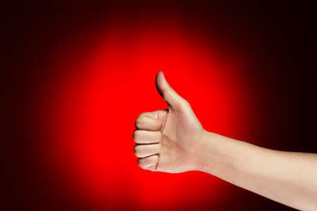 man shows thumb up over red backgroundの写真素材