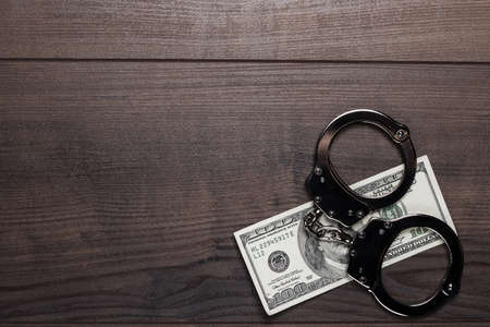 handcuffs and one hundred dollars on wooden tableの写真素材
