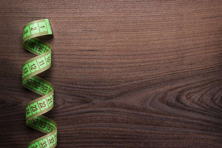 green measuring tape over wooden background
