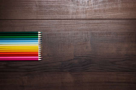 different pencils over brown table background
