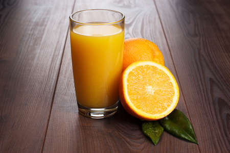 fresh orange and glass with juice on the tableの写真素材
