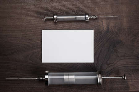 retro medical syringes and blank notebook over wooden backgroundの写真素材