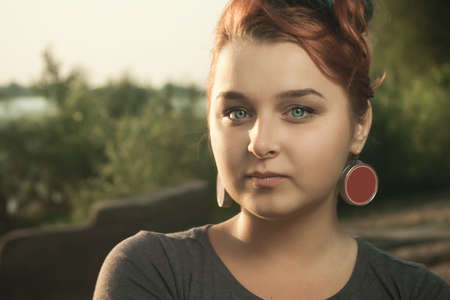 young red-haired woman standing on the river bankの写真素材