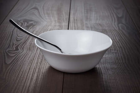 empty bowl with spoon on brown wooden tableの写真素材