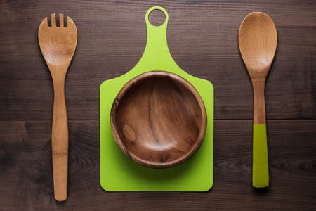 empty salad bowl and two spoons on wooden table