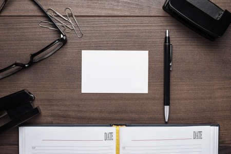 office brown wooden table with pen glasses and notebook backgroundの写真素材