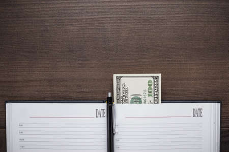 office brown wooden table with pen and notebook backgroundの写真素材