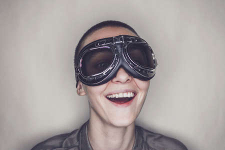 happy butch girl in retro pilot glasses over grey backgroundの写真素材
